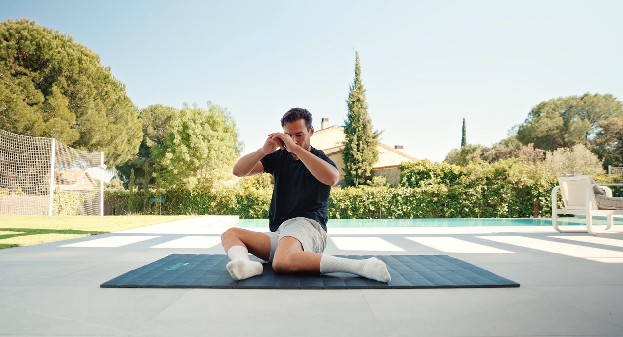 Hombre estirando sobre el tatami Kaizen Pro al aire libre